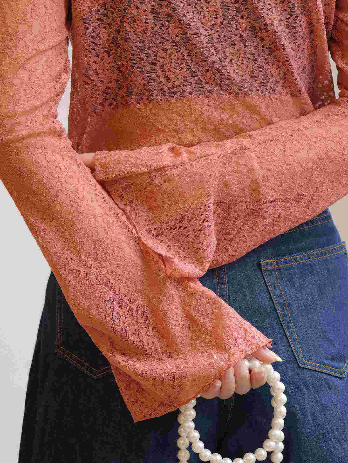 Close-up of lace fabric on see through bell sleeve top